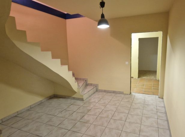 Malerarbeiten Raum mit Treppe, gelben Wänden und einem offenen Durchgang zu einem weiteren Zimmer.