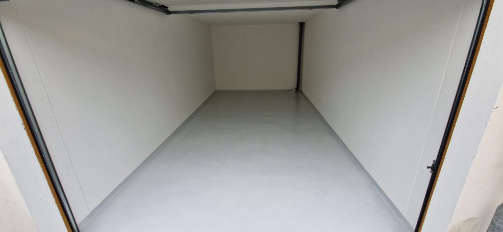 Wartungspaket Garage Ein leerer Raum mit weißen Wänden und glänzendem Boden, ohne Möbel oder Dekoration.