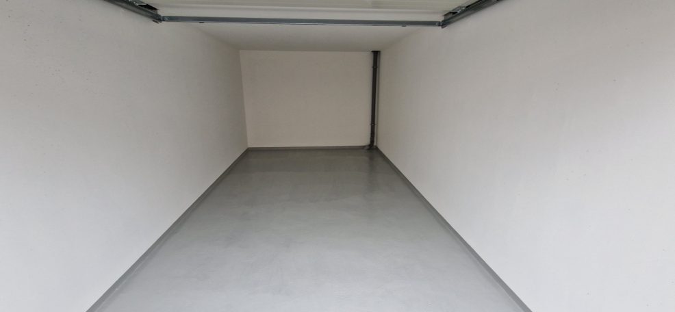 Wartungspaket Garage Leerer Raum mit weißen Wänden und einem grauen Boden.